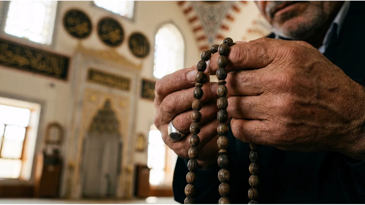 Gros plan sur des mains d'homme tenant un chapelet pour le dhikr en islam.