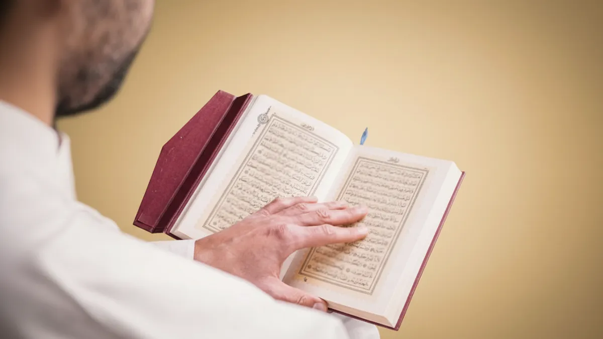 Mains d'un homme tenant un Coran et un chapelet